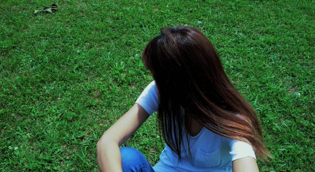 芝生に座って顔を背ける女性